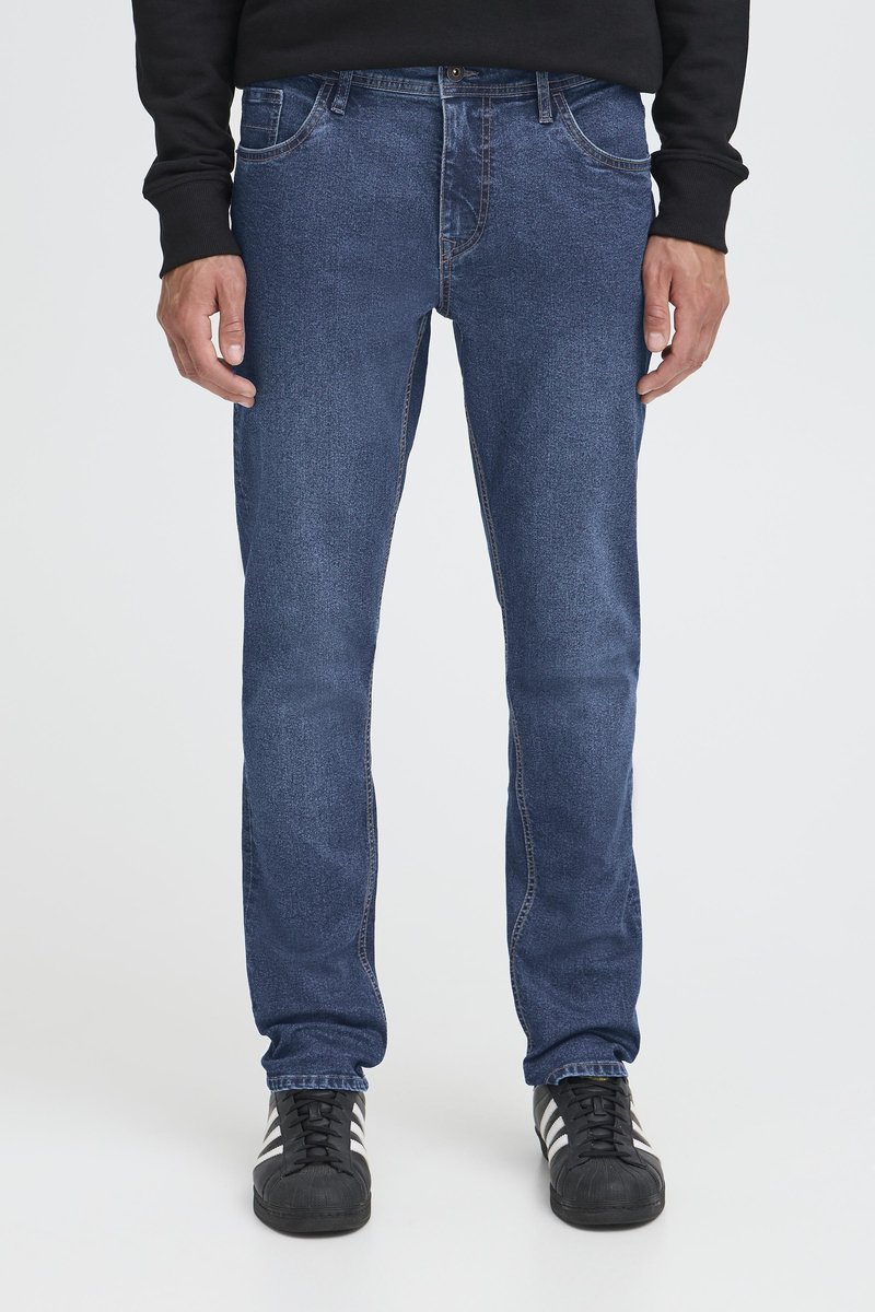 Mörkblå denimjeans med rak passform, utrustade med fem fickor och knäppning med knapp. Bärs med svarta sportskor.