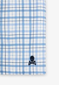 Tela a cuadros azul y blanca con un calavera y tibias cruzadas bordadas en azul marino, de textura suave y patrón de cuadros claro.