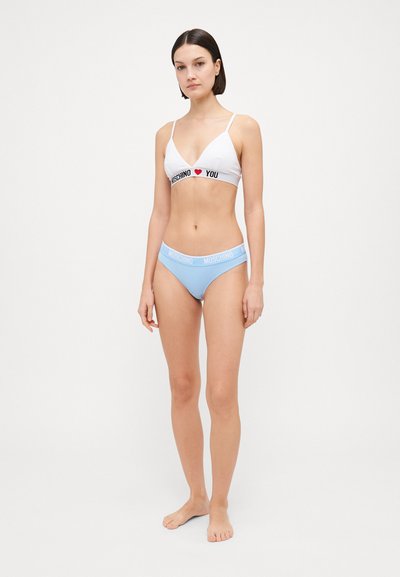 Biela podprsenka s čiernym potlačou "I ❤️ YOU" a svetlomodré bikiny, oboje s viditeľným nápisom Moschino. Jednoduchý dizajn a hladká textúra.