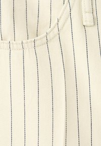 Tissu beige avec de fines rayures noires verticales et des coutures visibles délimitant une poche et une boucle de ceinture sur un matériau texturé.