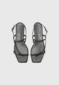 Svarte sandaler med stropper og firkantet tå. Laget av glatt materiale, med myke stropper og flat såle, i et minimalistisk design.
