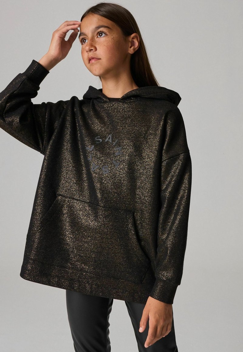 Sudadera negra con brillo y un ajuste relajado, con un bolsillo frontal y un diseño de logo circular. Textura suave, capucha ajustable.