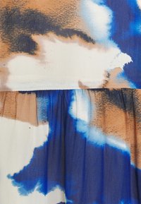 Kangas dengan pola abstrak dalam nuansa beige, biru, dan putih. Kain ringan dengan tekstur berkerut di sepanjang jahitannya.