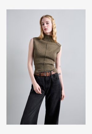 Olijfgroene mouwloze gebreide top met een hoge kraag, een gestructureerde afwerking en een brede geribbelde tailleband, gecombineerd met zwarte wijde broek en een bruine riem.