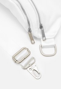 Biały kącik torby z dwoma srebrnymi zamkami błyskawicznymi, białym regulowanym paskiem i srebrnym metalowym zaczepem oznaczonym "Fiorucci" na białym tle.