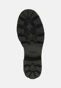Zwarte rubberen schoenzool met een gestructureerd loopvlakpatroon en het logo "GUESS". Heeft diepe groeven en een gestructureerd ontwerp voor grip.