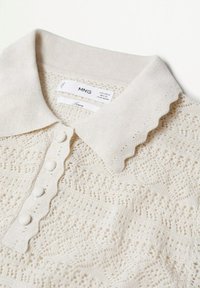 Leinen-Polohemd in hellbeige mit gewelltem Kragen, fünf Knöpfen und strukturiertem, offenen Strickmuster. Minimale Markenkennzeichnung sichtbar.