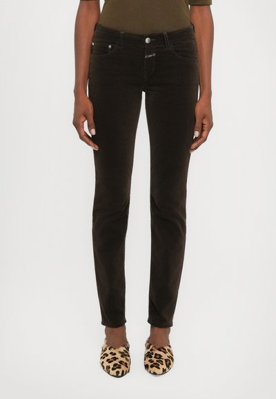 Jeans skinny en velours côtelé noir avec une finition à cinq poches, des coutures avant discrètes et une fermeture à bouton, associés à des chaussons imprimé léopard.