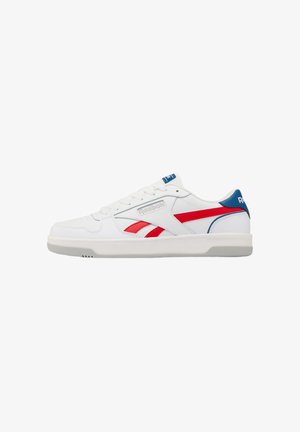 Sneaker bianco low-top Reebok con accenti rossi e blu, chiusura con lacci e suola piatta in gomma, mostrato di lato su sfondo bianco.