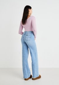 Lys blå høy midjebrede bein jeans med løs passform, med baklommer. Kombinert med en tettsittende langermet pastellrosa topp.