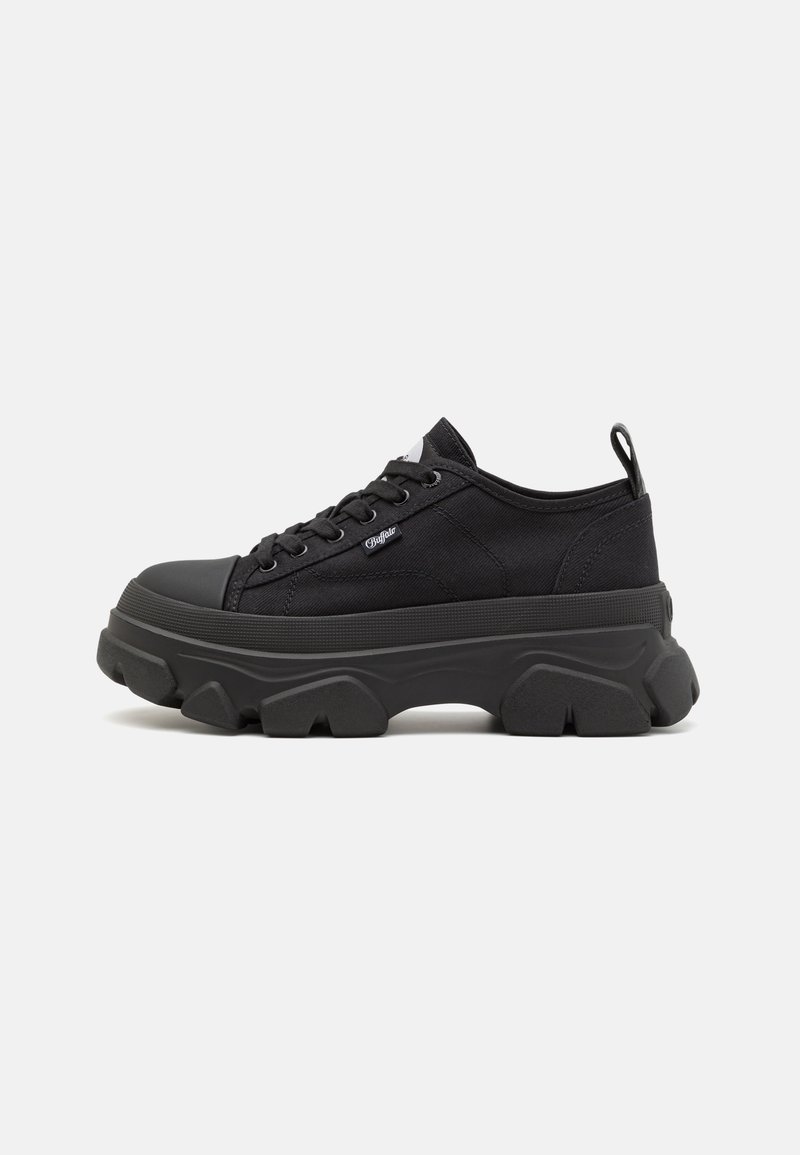 Black canvas sneakers with thick rubber soles, rounded toe, flat laces, and a pull tab at the heel. Features a textured surface and logo detail.