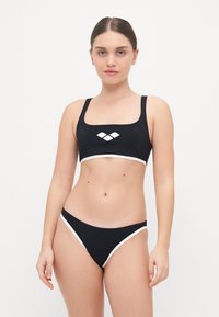 Completo bikini nero con top a scollo quadrato e rifiniture bianche, abbinato a slip a vita bassa con dettagli laterali bianchi.