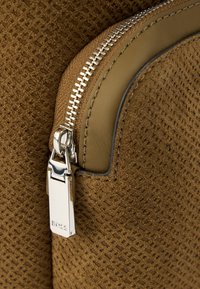 Γωνία καφέ τσάντας από δερματίνη με ασημένιο φερμουάρ και μεταλλικό στοιχείο, με ορθογώνιο έλκηθρο χαραγμένο με τη λέξη "BOSS".