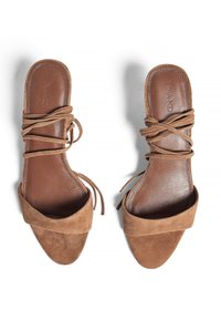 Brown suede slide sandals with a wide strap and tied laces. The insoles feature a smooth leather texture, creating a contrast with the upper material.