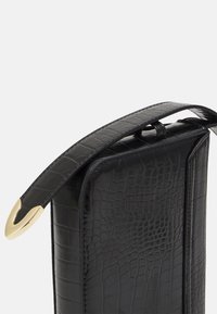 Borsa nera in pelle con stampa a coccodrillo e finitura lucida. Dotata di una tracolla piatta con hardware dorato e una forma rettangolare elegante.