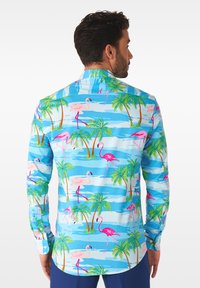 Lichtblauw overhemd met knopen en een tropisch patroon van roze flamingo's en groene palmbomen, voorzien van lange mouwen en een kraag.