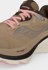 Μπεζ και καφέ παπούτσι τρεξίματος Saucony με ροζ κορδόνια, γκρι λογότυπο, αναπνεύσιμο επάνω μέρος από δίχτυ και μαύρη-λευκή μαλακή σόλα με κείμενο "incredilux".