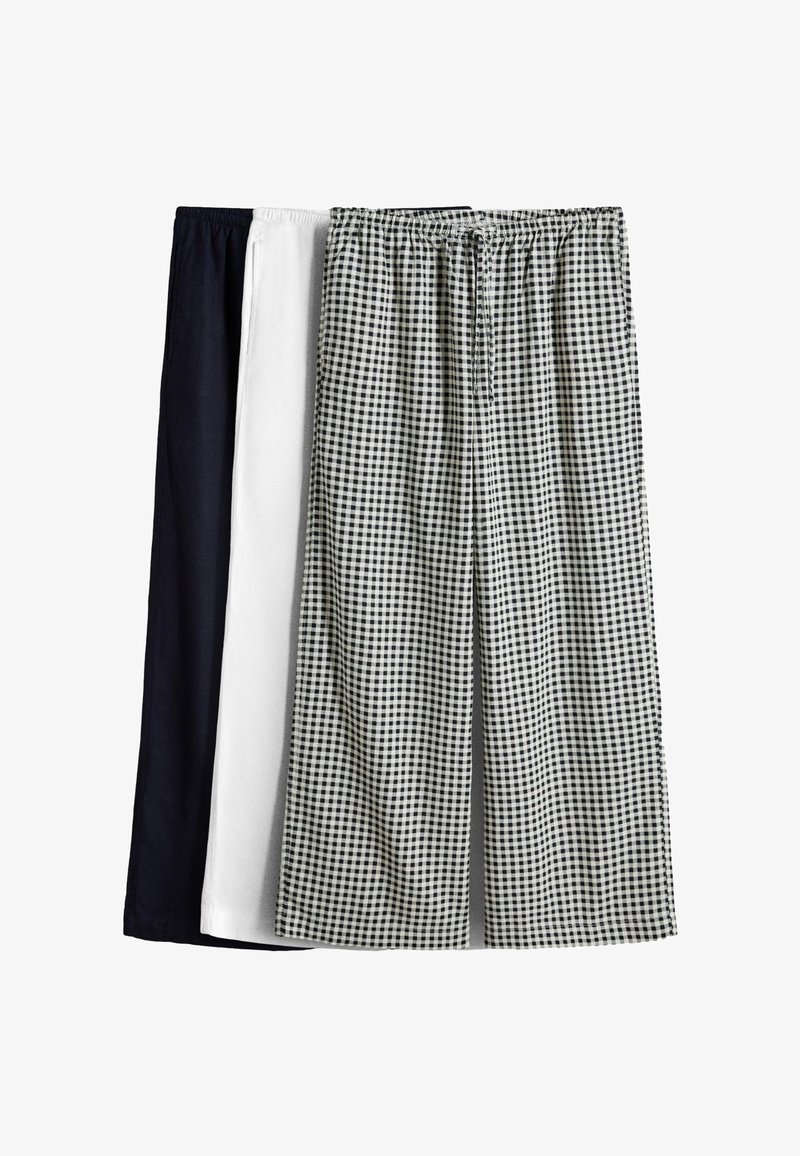 Trei perechi de pantaloni cu talie elastică în negru, alb și model în carouri alb-negru, expuse unul lângă altul.