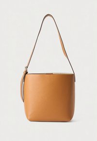 Schultertasche aus cognacfarbenem Leder mit glatter Oberfläche, abgerundeter Form und einem einzelnen verstellbaren Riemen. Mit einem dezenten metallischen Akzent versehen.