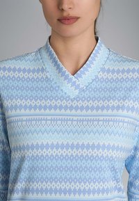 Top azzurro chiaro con motivo, caratterizzato da un colletto a V, con design intricati in blu scuro e bianco, realizzato in un tessuto morbido.