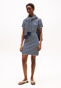 Navy and white striped short-sleeve dress with a round neckline, paired with a striped scarf and white flip-flops. Accessories include a purse.