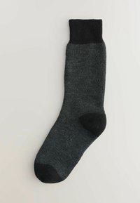 Calcetín gris con puño acanalado negro, textura suave, puntera y talón reforzados. Color sólido, de longitud media hasta la pantorrilla con un diseño minimalista.