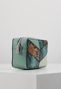 Borsa cosmetica rettangolare color teal con zip argentata e un pannello frontale di patchwork di pannelli con texture a pelle di serpente in tonalità teal, marrone e beige su superficie bianca.