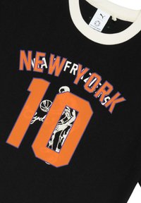 Sort t-shirt med en cremefarvet krave, der har "NEW YORK" skrevet i orange og blå tekst, "10" i klart orange og en basketballgrafik i hvid.