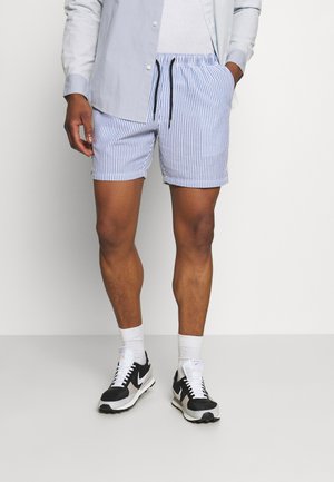 Light blue and white striped shorts with an elastic waistband and drawstring. Paired with black sneakers and white socks.
