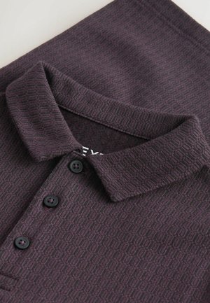 Polo shirt violet sombre avec un motif géométrique texturé, arborant un col doux et trois boutons noirs.