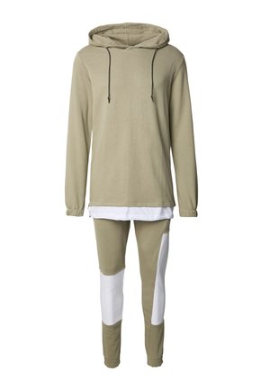 Kapuzensweatshirt in hellem Olivgrün mit schwarzen Kordeln, kombiniert mit engen, olivgrünen Leggings mit weißen Einsätzen. Hergestellt aus Baumwollmischgewebe.
