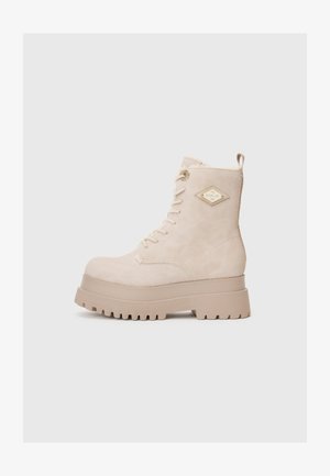 Beige színű, magas szárú, fűzős csizma vastag gumitalppal és Replay logóval az oldalán, egyszerű háttér előtt bemutatva.