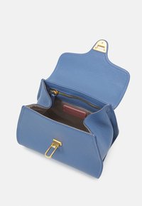 Niebieska skórzana torebka o fakturowanej powierzchni, z pozłacanym okuciem, klapą zamykającą oraz wewnętrzną kieszenią na zamek. Wyściełana jasnym materiałem.
