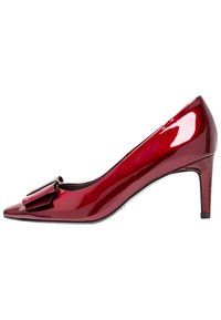 Escarpin à talon haut en cuir verni rouge avec un bout pointu et un nœud décoratif sur la tige. Dispose d'un talon fin et d'une texture lisse.