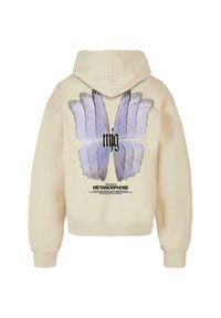 Sweat à capuche crème avec un grand motif de papillon violet dans le dos, accompagné d'un texte noir en dessous précisant "L'histoire de la métamorphose."
