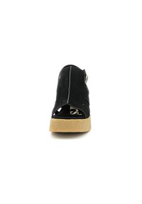 Sandalo in suede nero con punta aperta, ritagli laterali e una fascia regolabile. Presenta una suola in sughero beige testurizzato per il comfort.