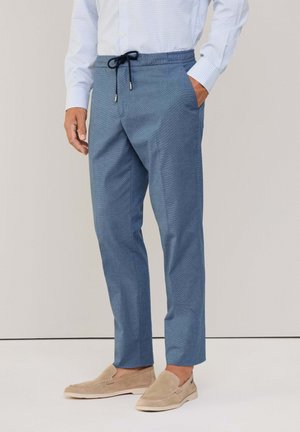 Lichtblauwe, gestructureerde broek met een elastische tailleband en trekkoord, met zijzakken en taps toelopende benen, gecombineerd met beige instappers.