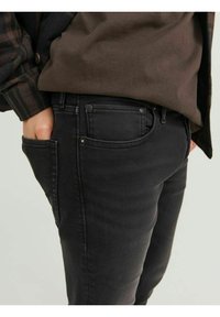 Jeans in denim nero con una vestibilità slim, caratterizzati da un design a cinque tasche e dettagli di cucitura visibili. Il materiale ha una leggera texture.