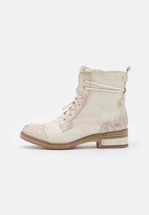 Bottine beige à lacets avec bout et talon à motifs, petit talon empilé et lacets décoratifs enroulés sur le côté.