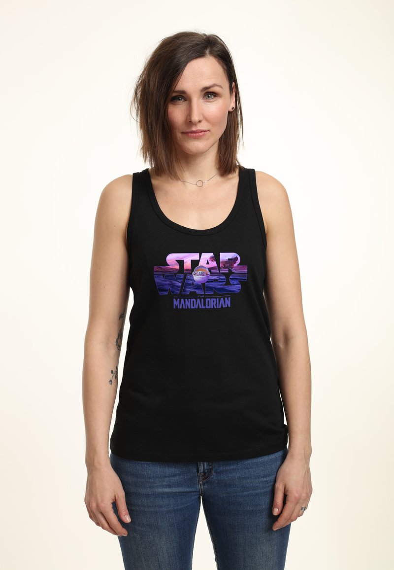 Černý tílko s grafikou v purpurových a růžových tónech s textem "STAR WARS MANDALORIAN". Tkanina vypadá měkce; střih je volný.