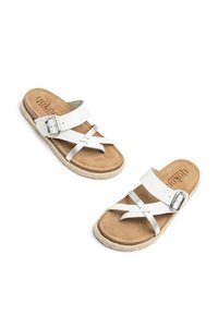 Witte leren sandalen met metallic accenten, verstelbare gesp en een kurkzool. Heeft een platte uitstraling en een kruisriemstructuur.