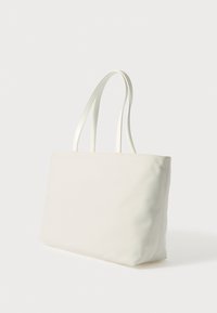 Valge kangast kandekott, sileda tekstuuriga, kahe lameda sangaga ja minimalistliku ristkülikukujuga.