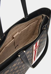 Sac fourre-tout noir avec un extérieur à motifs, quincaillerie dorée et un accent rayé. Doublure intérieure beige avec le logo de la marque en répétition.