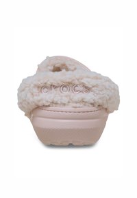 Lichtroze Crocs met een fluffy, faux fur voering en een geprofileerde rubberen zool. De merknaam "CROCS" is op de achterkant gestikt.