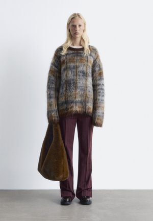 Mohair blend sweater with brown, grey, and blue stripes, paired with burgundy pinstripe trousers and a brown fur-like tote bag. Black shoes.