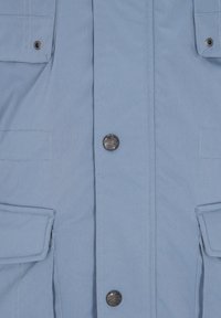 Chaqueta azul claro vista frontal con cuatro bolsillos con solapa y botones a presión de metal con relieve de texto.