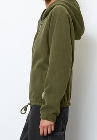 Giacca a cappuccio verde oliva con chiusura con zip, polsini elastici e cordino regolabile in fondo. Tessuto morbido, design casual.