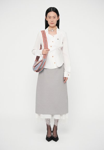 Balta ar pogām apveltīta krekla krekls ar oranžām pogām, pelēks svārks, kārtaina balta mežģīne un melni smaili augsti papēži. Pelēka un sarkana svītraina plecu soma.