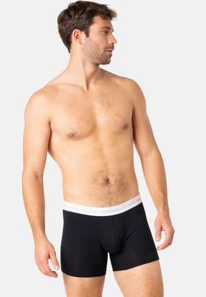 Caleçon noir en coton avec une ceinture élastique blanche, présentant une texture lisse et un design ajusté. Pas de motifs ou d'accents visibles.