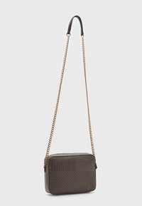 Borsa a tracolla grigia in ecopelle con design trapuntato, dotata di tracolla nera e dettagli in catena dorata. Chiusura con zip sulla parte superiore.
